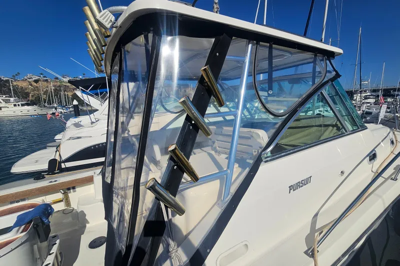 Slide: The Image of 2001 Pursuit 3000 Express boat docked in marina, featuring clear enclosure and rod holders. - 28