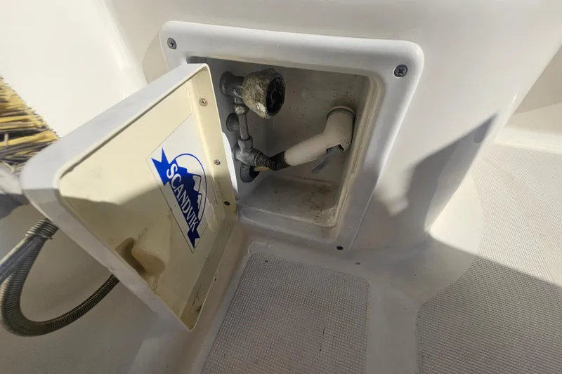 Slide: The Image of Open compartment on 2001 Pursuit 3000 Express boat with Scandvik label and plumbing components. - 29