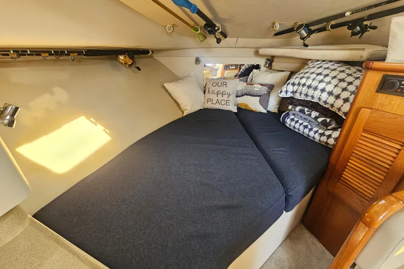 Slide: The Image of Cozy cabin interior of 2001 Pursuit 3000 Express with bed and fishing rods. - 34