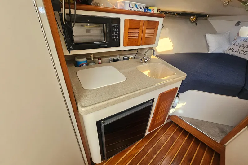 Slide: The Image of Compact kitchen area in a 2001 Pursuit 3000 Express boat with sink and microwave. - 35