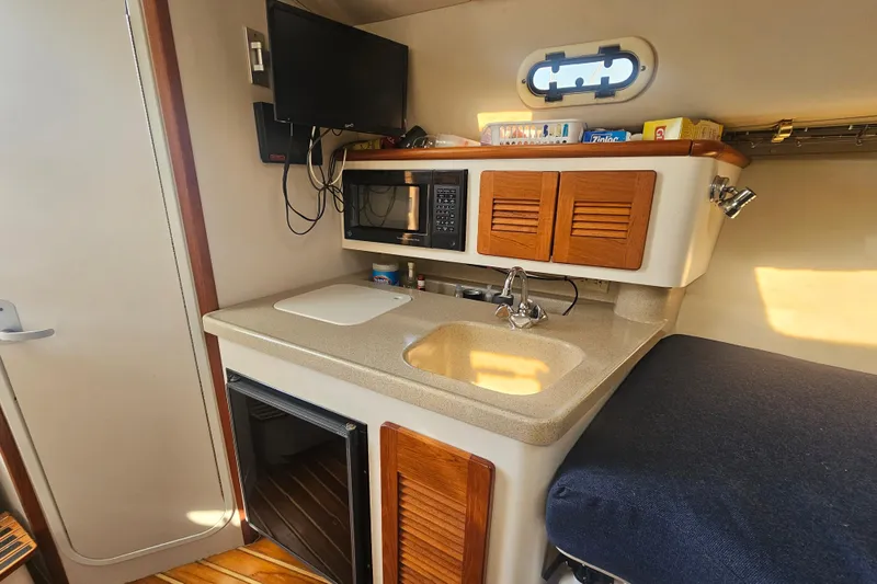 Slide: The Image of 2001 Pursuit 3000 Express boat interior with kitchenette, sink, microwave, and storage cabinets. - 36