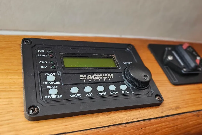 Slide: The Image of Magnum Energy control panel on 2001 Pursuit 3000 Express boat, mounted on wooden surface. - 47