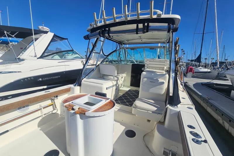 Slide: The Image of 2001 Pursuit 3000 Express boat docked, featuring spacious seating and fishing rod holders. - 9
