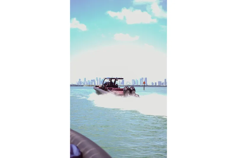 Slide: The Image of 2024 Skipper 42 boat cruising on water with city skyline in background. - 42