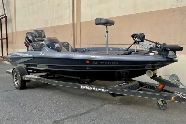 Slide: The Image of 2013 Triton 18XS bass boat on trailer, parked outdoors. - 2