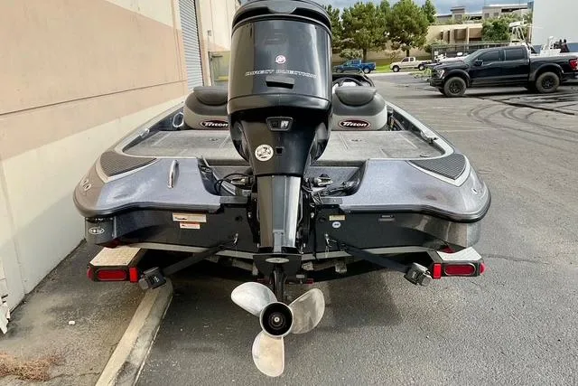 Slide: The Image of 2013 Triton 18XS boat with outboard motor, parked outdoors on pavement. - 4
