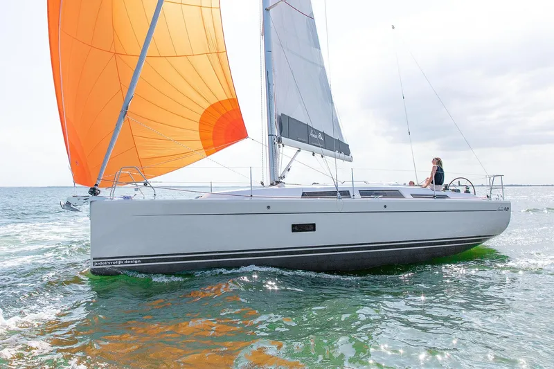 The Image of 2026 Hanse 348 sailboat with orange sail cruising on open water. - 0