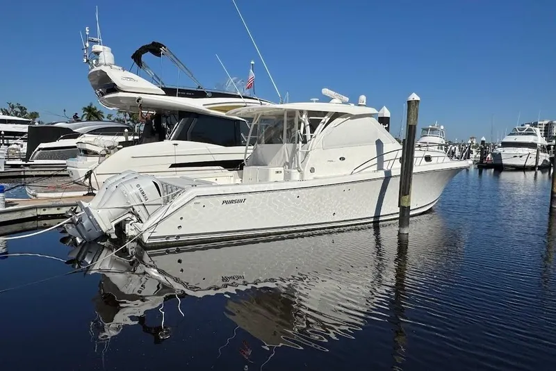 Slide: The Image of 2021 Pursuit OS 385 Offshore boat docked in a marina, reflecting on calm water. - 37