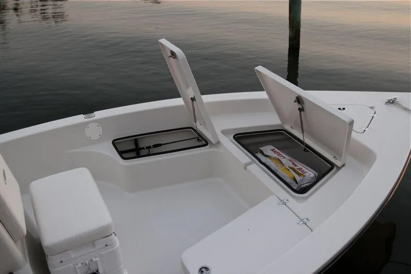 Slide: The Image of Manufacturer Provided Image: 2019 Cobia 21 Bay boat with open storage compartments on calm water. - 11