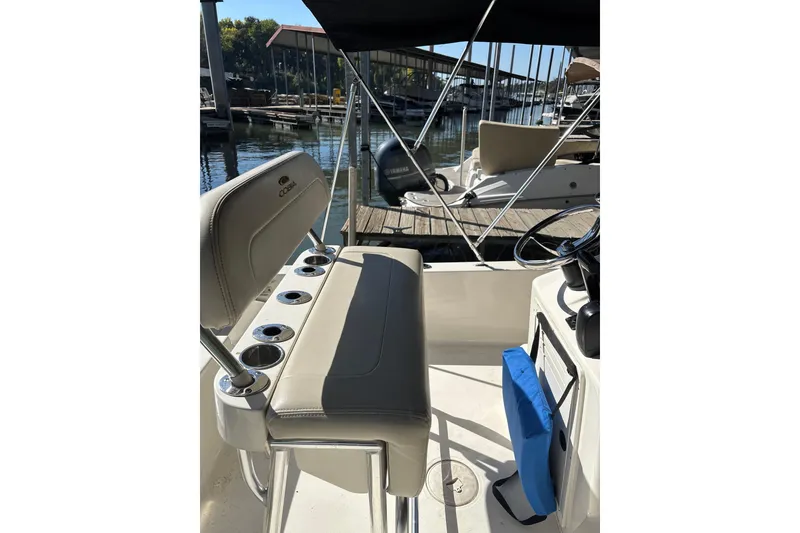 Slide: The Image of 2021 Cobia 21 Bay boat interior with seating and steering wheel at marina. - 2