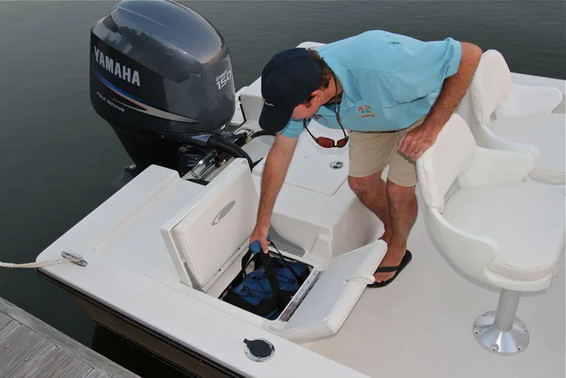 Slide: The Image of Manufacturer Provided Image: Man accessing storage compartment on 2019 Cobia 21 Bay boat with Yamaha outboard motor. - 21