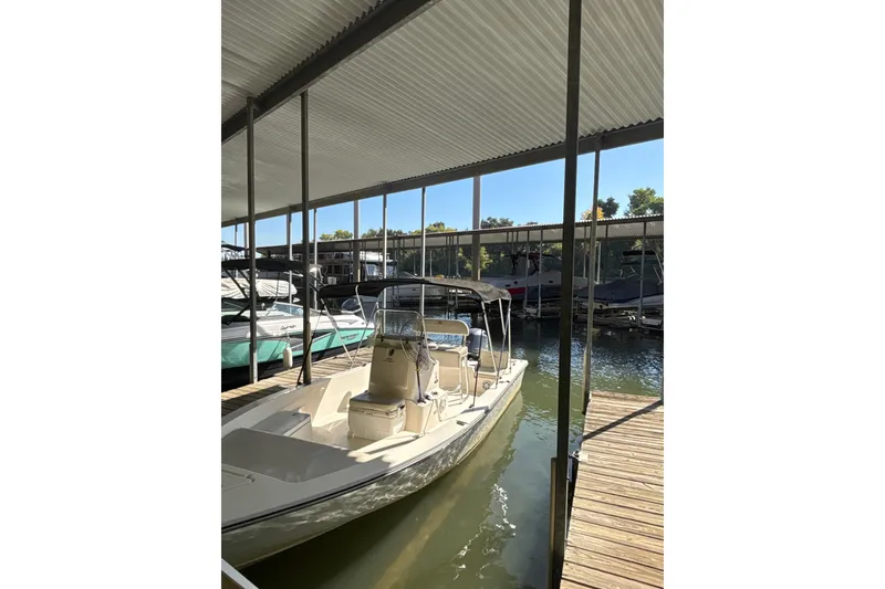 Slide: The Image of 2021 Cobia 21 Bay boat docked under covered marina, surrounded by water and other boats. - 3