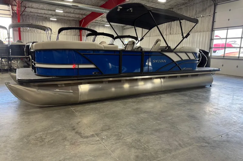 Slide: The Image of 2026 Sylvan X5 pontoon boat in showroom, featuring blue exterior and canopy. - 3