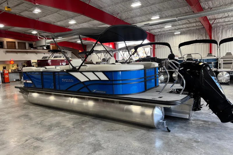 Slide: The Image of 2026 Sylvan X5 pontoon boat in showroom, featuring blue and white design. - 4