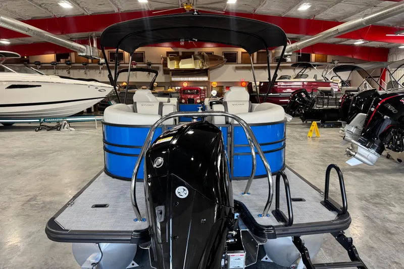 Slide: The Image of 2026 Sylvan X5 pontoon boat in showroom, featuring blue and white seating. - 5