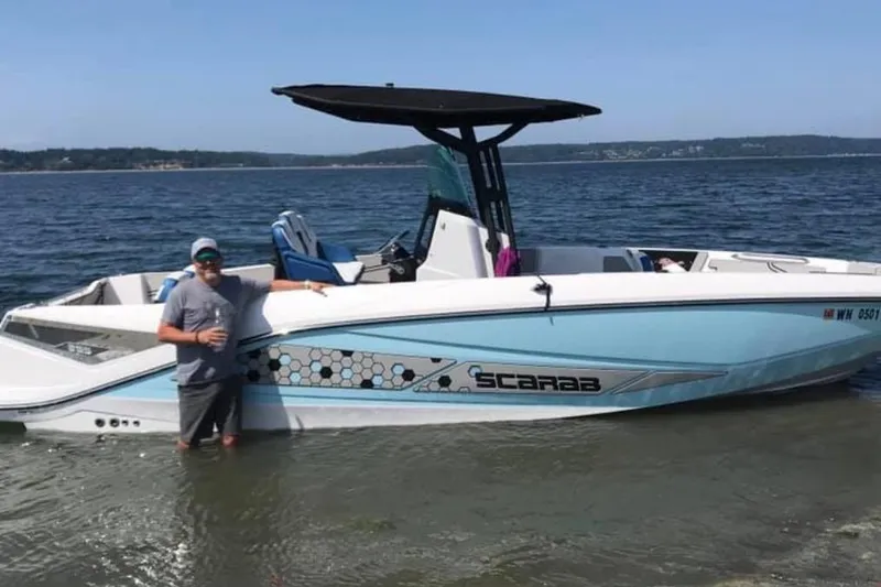 Slide: The Image of 2018 Scarab 255 Open ID boat in shallow water with a person standing nearby. - 10