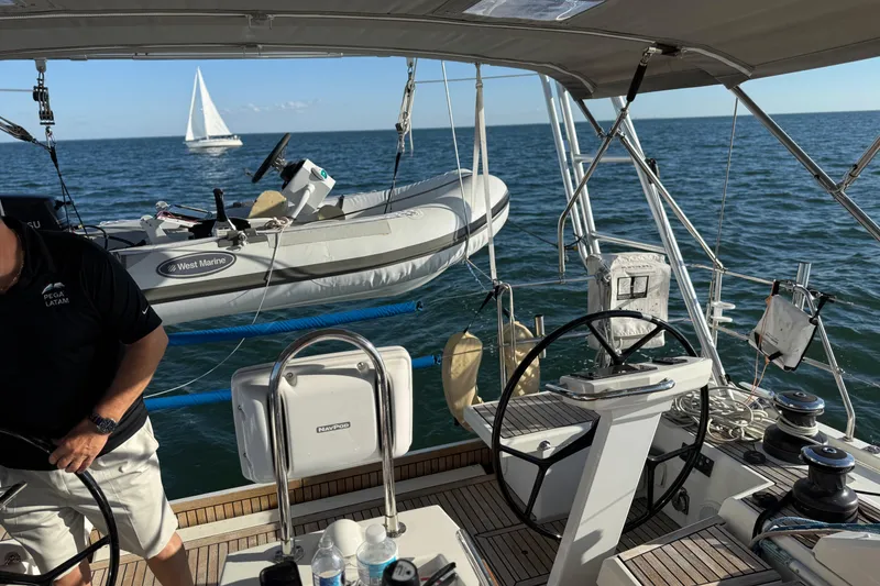 Slide: The Image of Cockpit view of 2020 Beneteau Oceanis 51.1 sailboat with dinghy and ocean backdrop. - 55