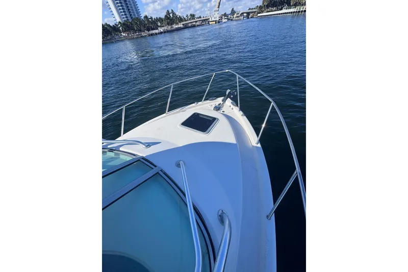 Slide: The Image of 2014 Robalo R265 Walkaround boat on calm water near a cityscape. - 10