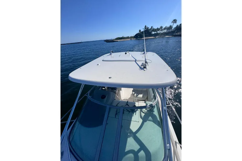 Slide: The Image of 2014 Robalo R265 Walkaround boat on calm water, clear sky, palm trees in background. - 13