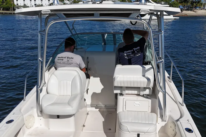 Slide: The Image of 2014 Robalo R265 Walkaround boat with two people seated, cruising on calm water. - 14