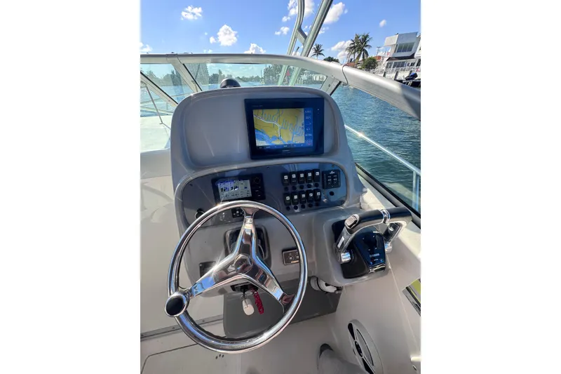 Slide: The Image of 2014 Robalo R265 Walkaround helm with navigation display and controls, docked by water. - 26