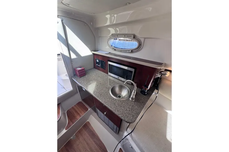 Slide: The Image of 2014 Robalo R265 Walkaround boat interior with kitchenette, sink, and microwave. - 42