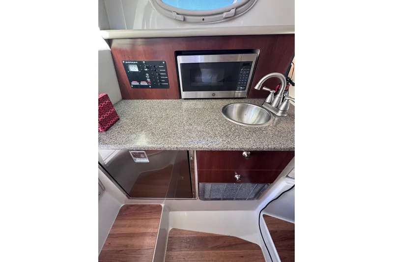Slide: The Image of 2014 Robalo R265 Walkaround boat interior with microwave, sink, and wooden flooring. - 43