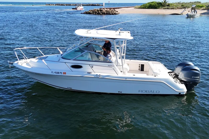 Slide: The Image of 2014 Robalo R265 Walkaround boat on water with Yamaha engines, near a sandy shore. - 5