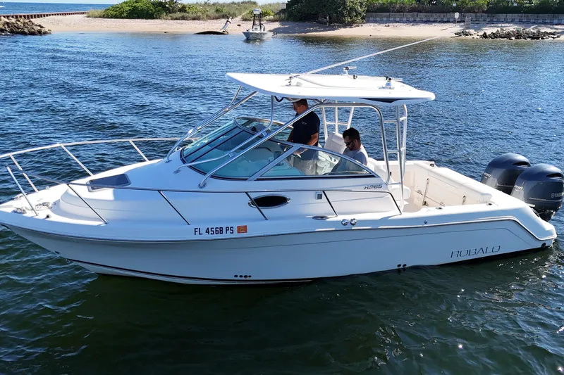 Slide: The Image of 2014 Robalo R265 Walkaround boat on water, featuring dual outboard engines. - 6