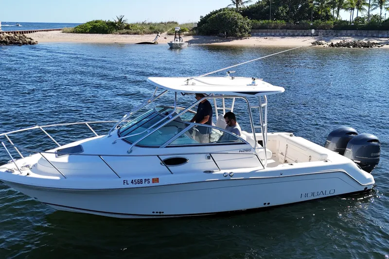 Slide: The Image of 2014 Robalo R265 Walkaround boat cruising near a sandy beach with two passengers. - 7