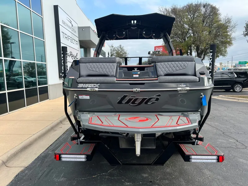 Slide: The Image of 2026 Tigé 24RZX boat rear view, parked outside dealership, showcasing sleek design and branding. - 4