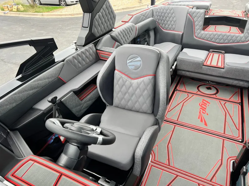 Slide: The Image of 2026 Tigé 24RZX boat interior with gray and red upholstery, featuring a modern steering wheel. - 49