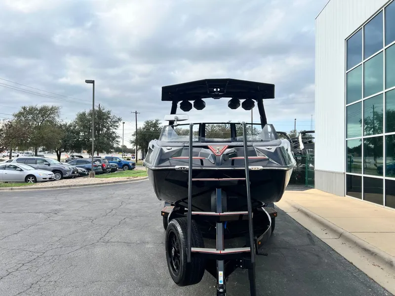 Slide: The Image of 2026 Tigé 24RZX boat on trailer, parked outside a building under cloudy skies. - 9