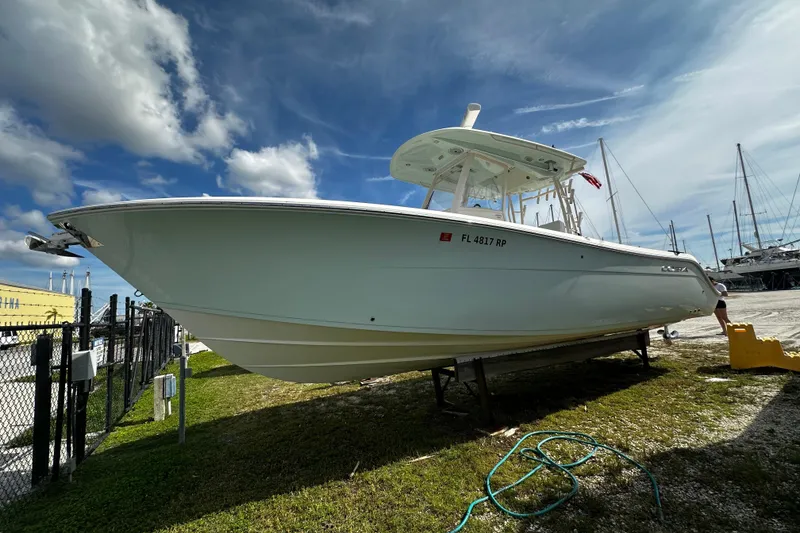 The Image of 2018 Cobia 301 Center Console boat on land under a partly cloudy sky. - 0