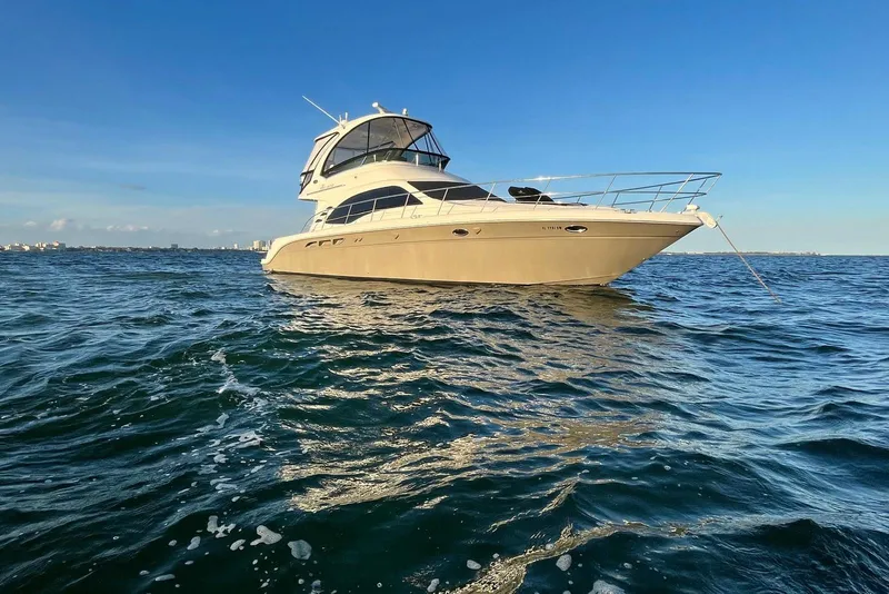 Slide: The Image of 2006 Sea Ray 52 Sedan Bridge yacht on open water under clear blue sky. - 2