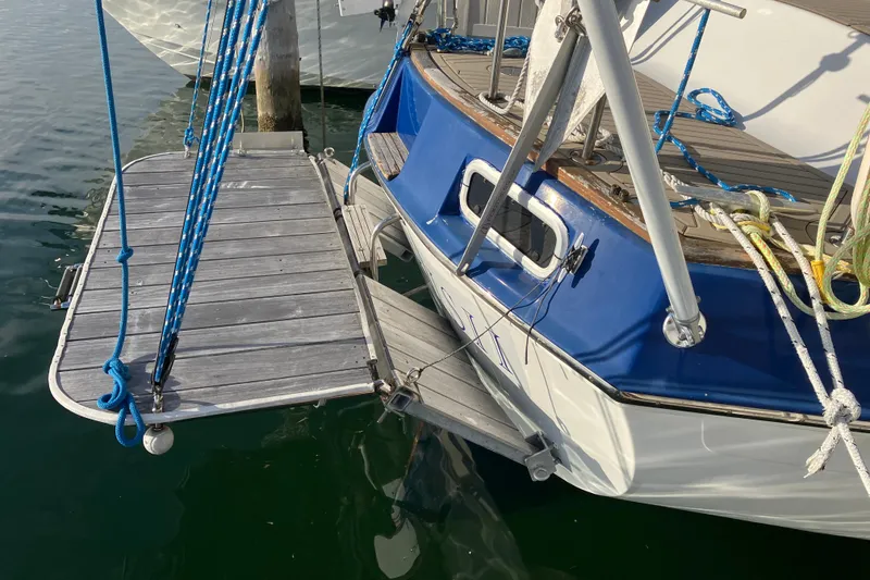 Slide: The Image of 1987 Morgan Classic 41 sailboat with blue and white hull, docked with wooden platform. - 14