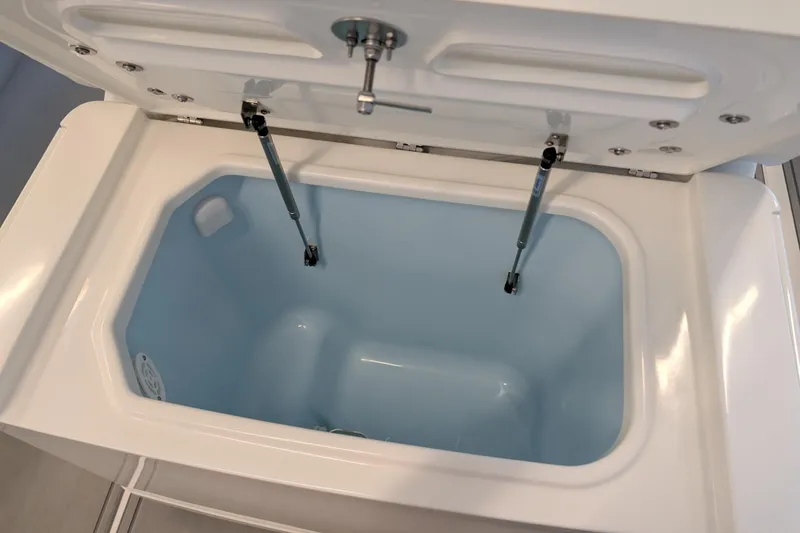 Slide: The Image of Open storage compartment in 2026 Mako 24 APEX boat, featuring hydraulic lift supports. - 14