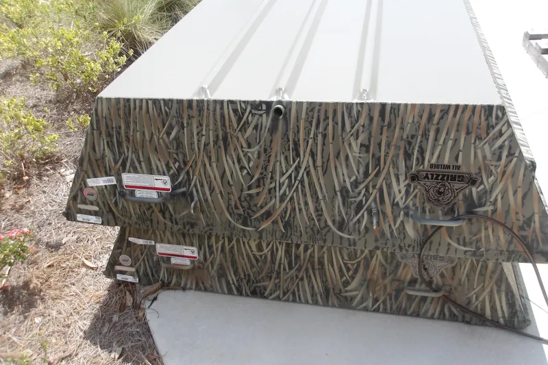 Slide: The Image of 2026 Tracker Grizzly 15 Jon boat with camouflage design, stacked outdoors. - 3