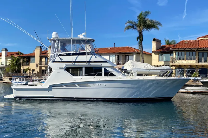 Slide: The Image of 1995 Hatteras 50 Convertible Sportfish yacht docked near waterfront homes. - 0