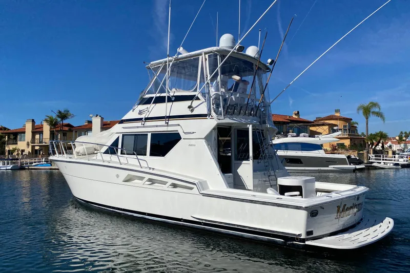Slide: The Image of 1995 Hatteras 50 Convertible Sportfish yacht docked in a marina under clear blue skies. - 1