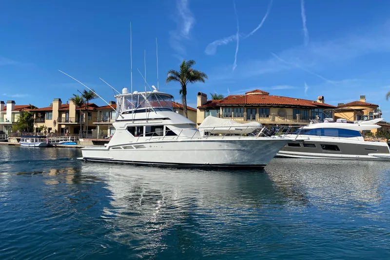 Slide: The Image of 1995 Hatteras 50 Convertible Sportfish yacht docked near waterfront homes. - 12