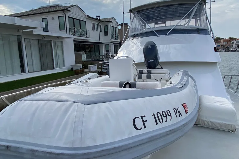 Slide: The Image of 1995 Hatteras 50 Convertible Sportfish with dinghy, docked near waterfront homes. - 23