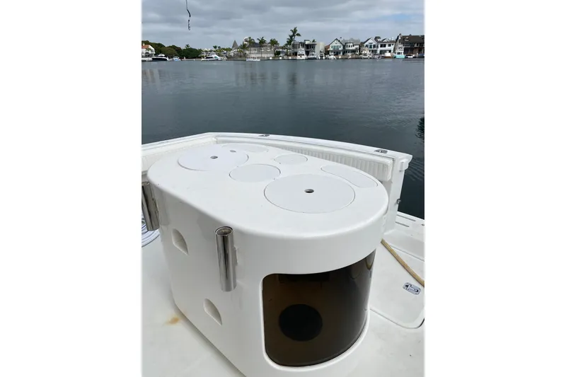 Slide: The Image of 1995 Hatteras 50 Convertible Sportfish boat deck with fishing equipment, docked by waterfront homes. - 24