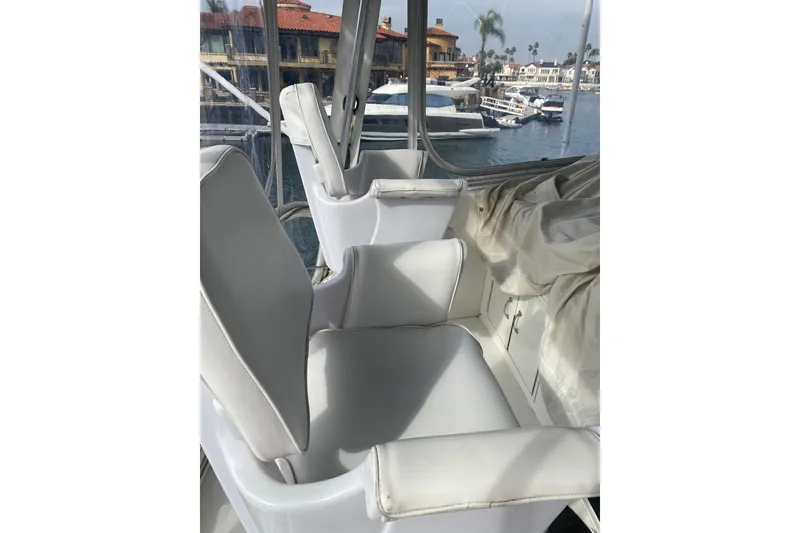Slide: The Image of Interior view of 1995 Hatteras 50 Convertible Sportfish with white seating and marina backdrop. - 33