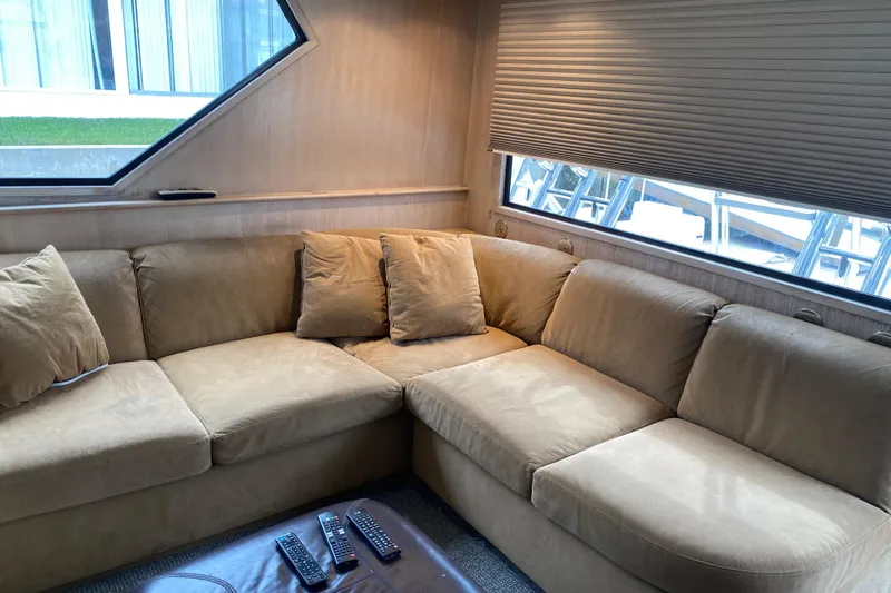 Slide: The Image of Interior of 1995 Hatteras 50 Convertible Sportfish with beige sectional sofa and remote controls. - 50
