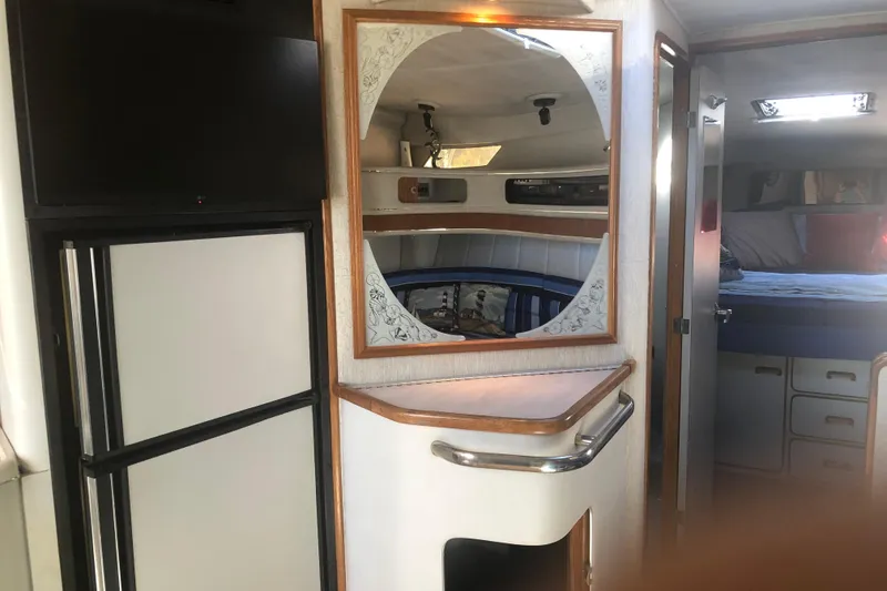 Slide: The Image of Interior of a 1990 Sea Ray 440 Express yacht, featuring a mirror, bed, and storage. - 13