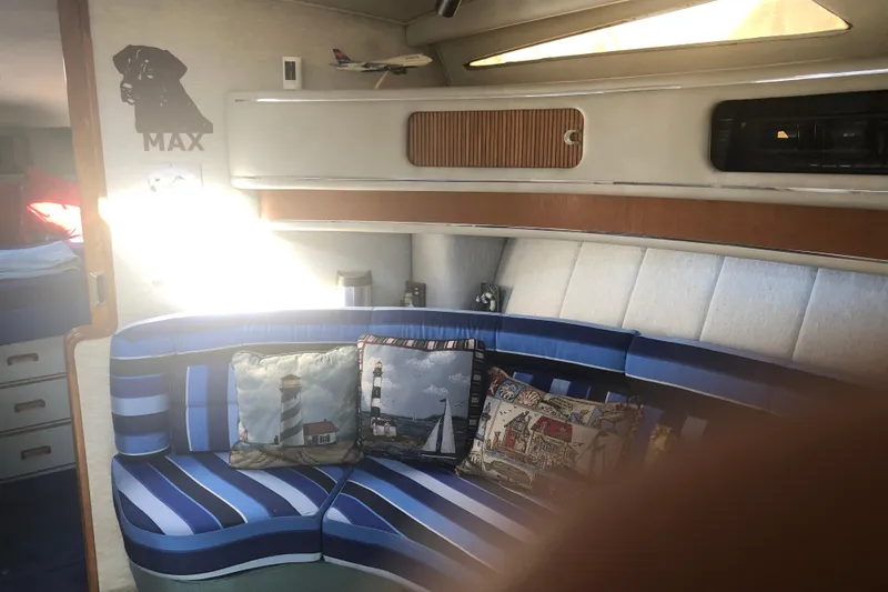 Slide: The Image of Interior of 1990 Sea Ray 440 Express with striped seating and nautical-themed pillows. - 14