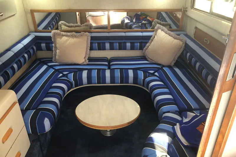 Slide: The Image of 1990 Sea Ray 440 Express interior with striped seating and round table. - 17