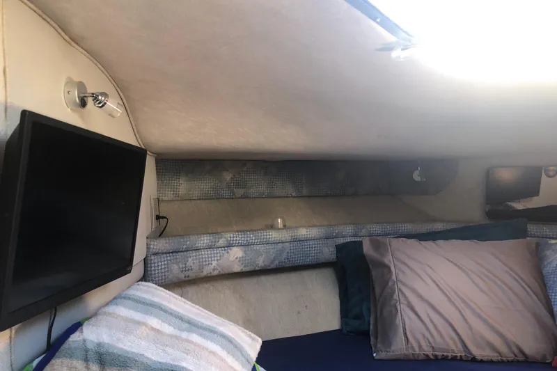 Slide: The Image of 1990 Sea Ray 440 Express cabin interior with TV and bedding. - 23