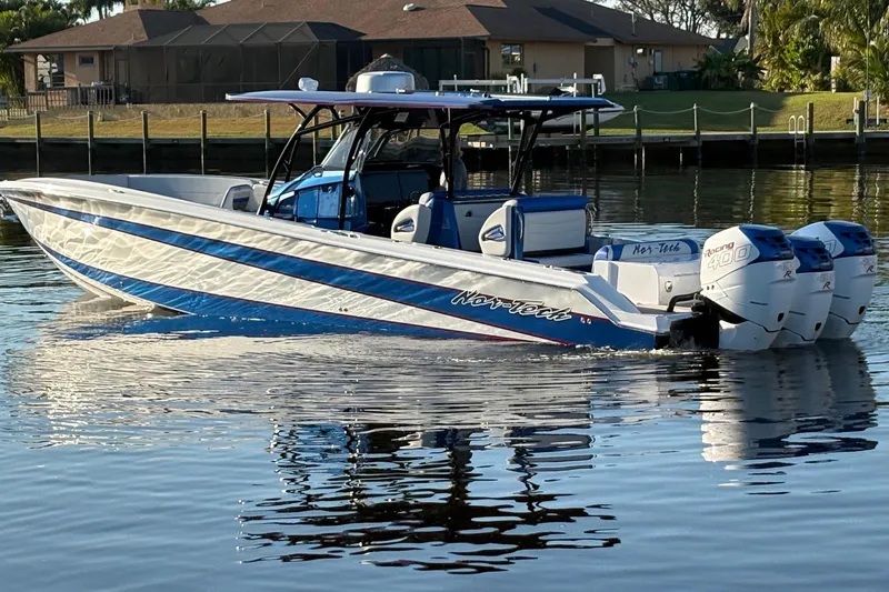 The Image of 2023 Nor-Tech 390 Sport Center Console boat on calm water, featuring triple outboard engines. - 0